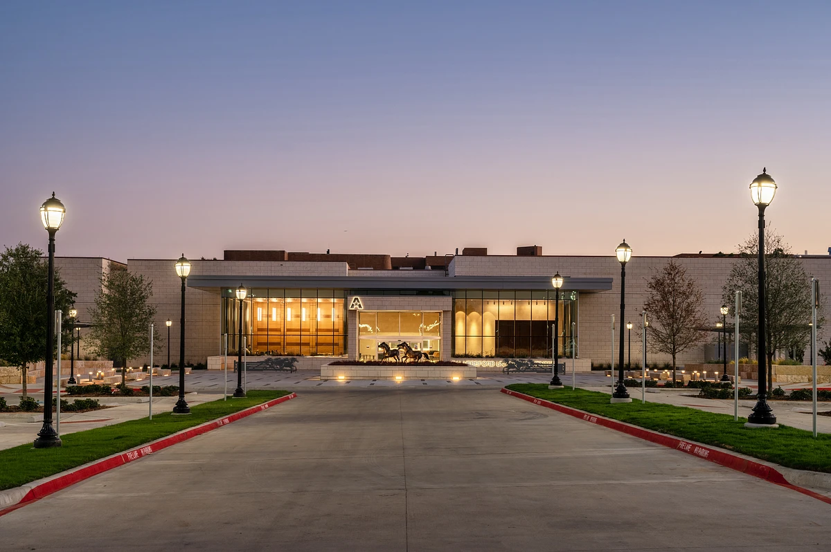 The UTA University Center is illuminated at dusk, with a central glass entrance flanked by streetlights and landscaping.